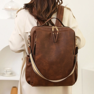 Detail eines dunkelbraunen Vintage-Rucksacks mit gestreiftem Gurt und Goldzippern