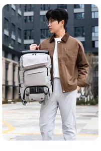 Detail of light gray travel backpack showing reinforced handle and side compression straps