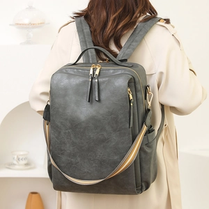 Detail eines dunklen Retro-PU-Lederrucksacks mit goldenen Zippern und Streifenriemen