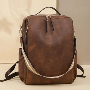Detail eines dunkelbraunen Vintage PU-Lederrucksacks mit bunt gestreiftem Schultergurt