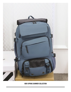 Macro shot of blue-grey travel backpack with multi-pocket storage and roll-top design