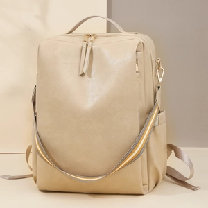 Detail eines beigen PU-Lederrucksacks mit gestreiftem Gurt und goldenen Reißverschlüssen