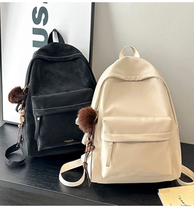 Detail of minimalist PU leather backpacks in black and beige with plush ball charms