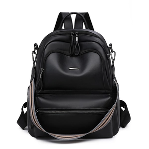 Detail of black leather backpack with silver zippers and striped woven shoulder strap