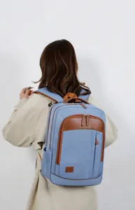 Light blue commute backpack with leather handle shown on a model in a minimal setting
