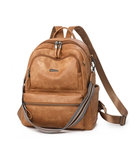 Detail view of brown vintage backpack featuring multiple zippers and striped strap