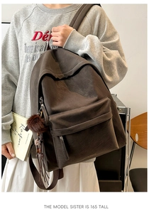 Detail of dark brown vintage PU leather backpack featuring white contrast stitching and tassels