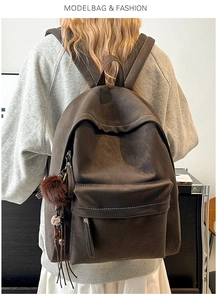 Detail view of large faux leather backpack with plush keychain and front zipper pocket