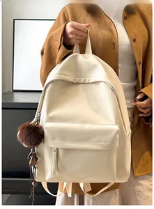 Detail of the minimalist beige PU leather backpack with front pocket and fur ball charm