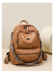Detail view of vintage brown leather backpack with multi-zipper pockets and metallic logo