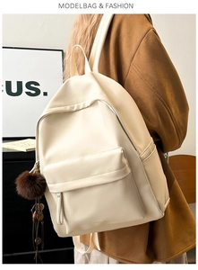 Close-up of cream PU backpack with large capacity and decorative brown pompom charm