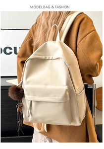 Detail of cream white PU leather backpack with flap pocket and plush charm on model