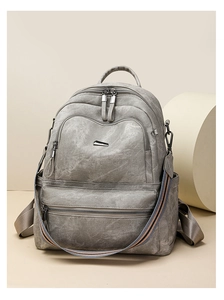 Detail of grey vintage leather backpack with multi-zipper pockets and striped shoulder strap