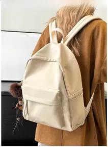 Detail of cream faux leather backpack featuring a plush charm and side drawstring pockets