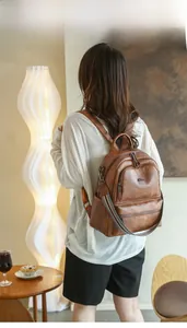 Close-up of a brown vintage PU leather backpack with multi-pocket design on model