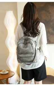 Grey vintage backpack with distressed texture and striped strap shown in cozy interior