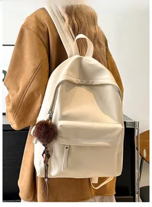 Detail showing the cream PU leather backpack worn by a model in a warm indoor setting