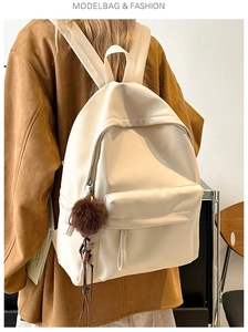 Detail of cream PU leather backpack with a decorative dark brown fluffy pompom on the front pocket