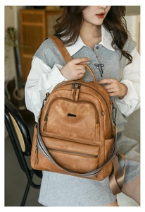Detail of vintage brown leather backpack with woven strap and matte texture shown on model