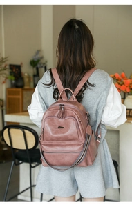 Detail of vintage pink backpack showing dual zippers and striped fabric shoulder strap