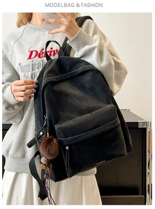 Detail view of black vintage PU leather backpack with contrast stitching and furry charm