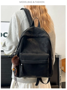Detail of black PU leather backpack with contrast stitching and brown fur pompom accessory