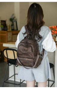 Detail of vintage brown backpack with metallic zippers and colorful woven strap