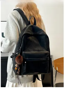 Detail of black PU backpack featuring contrast white stitching and plush ball charm
