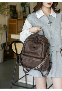Detail of vintage brown faux leather backpack with multiple pockets and bronze hardware