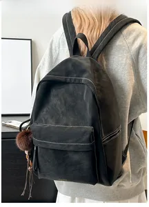 Detailed view of black PU backpack with contrast stitching and brown fluffy charm