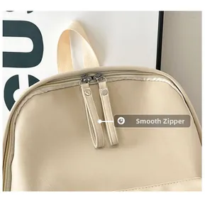 Detail view of smooth dual zippers and fine PU leather texture on the beige backpack