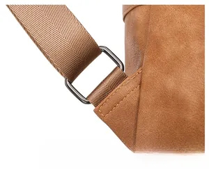 Detail of woven strap with sturdy metal ring and yellow stitching on brown backpack