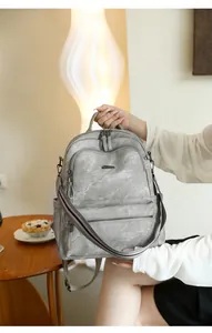 Detail of grey PU leather backpack featuring natural texture and metal zipper pockets