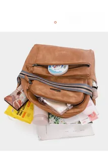 Brown faux leather backpack showing spacious main compartment filled with travel essentials