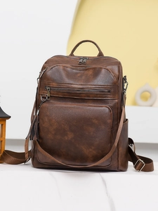Close-up of brown PU leather backpack featuring multi-zipper pockets and tassel detail