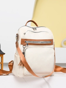 Detailed close-up of cream PU leather backpack featuring brown trim and silver metal zippers