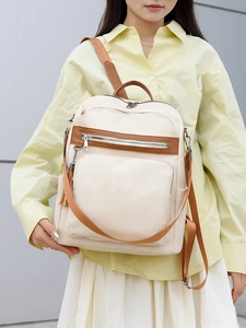 Detail of minimalist beige PU leather backpack with brown trim and side pocket