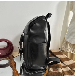 Side view of black PU leather backpack showing side pocket and fine grain texture detail