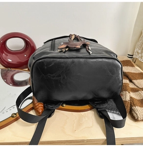 Detail of black PU leather backpack base with brown deer pendant and tassel charm