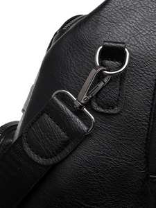Close-up of gunmetal hardware and litchi textured leather on a black backpack strap