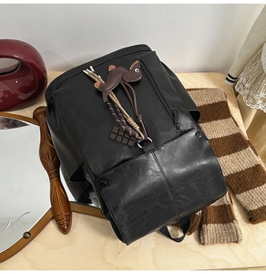 Detail view of a black PU backpack featuring creative charms and retro woven rope decor