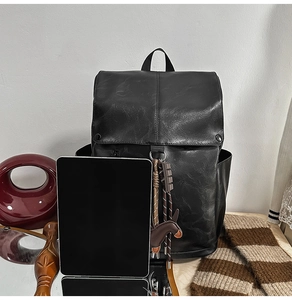 Detail view of large capacity PU leather backpack with tassel and horse charm and a tablet