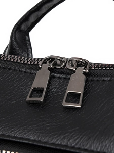 Close-up of dual silver zippers and litchi texture on a black PU leather backpack