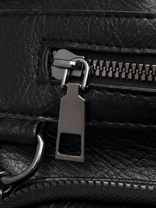 Detailed macro view of black litchi grain leather texture and metallic zipper