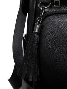 Detail of black pebbled PU leather backpack with tassel charm and gunmetal hardware