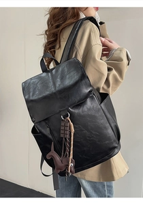 Side view of black faux leather backpack with decorative charms and side zipper detail