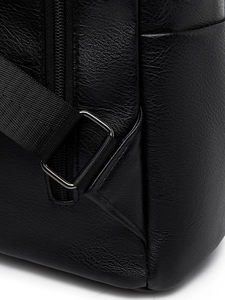 Close-up of black lychee grain PU leather backpack featuring metal buckles and nylon straps