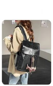 Detailed view of black textured PU leather backpack with side pockets and a cute dog charm