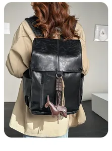 Detail of minimalist black PU leather backpack with vintage flap and cute dog charm