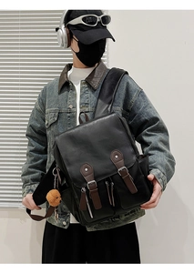 Detail eines schwarzen PU-Leder-Rucksacks mit braunen Riemen und Plüschbär-Anhänger